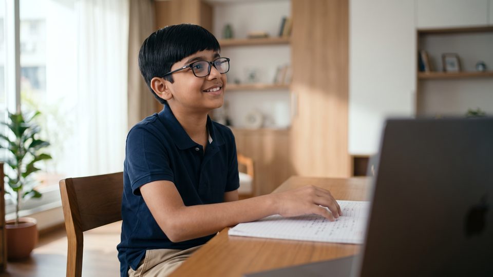 A boy covers his notes and recalls the lesson aloud with a growing smile