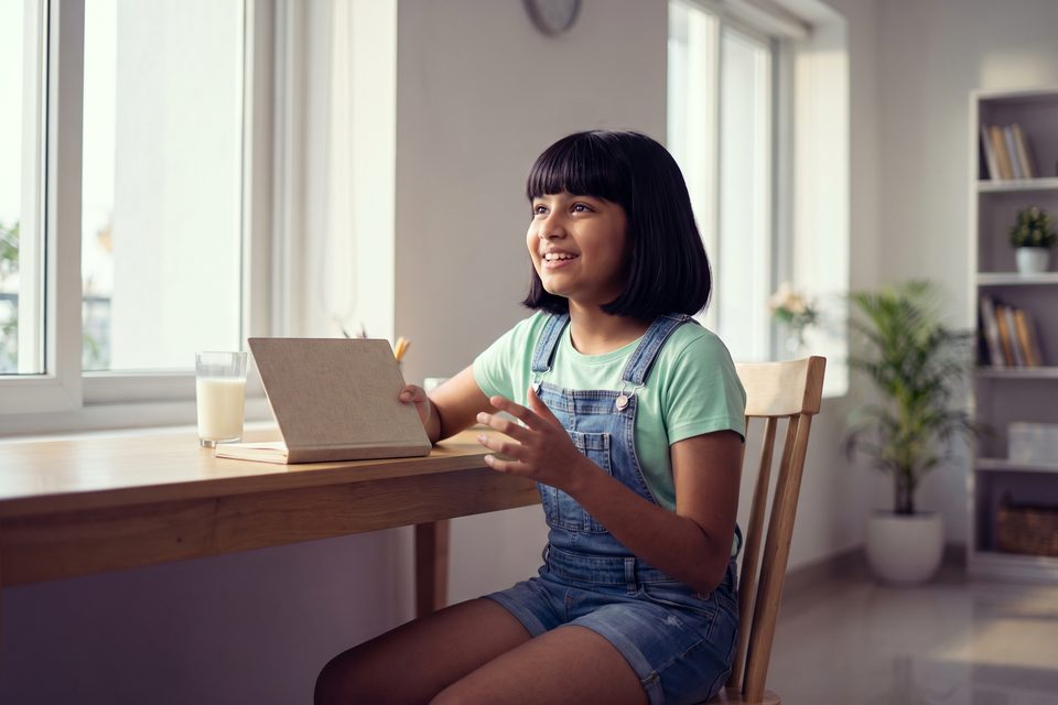 A girl recalls her lesson aloud at a sunny morning desk